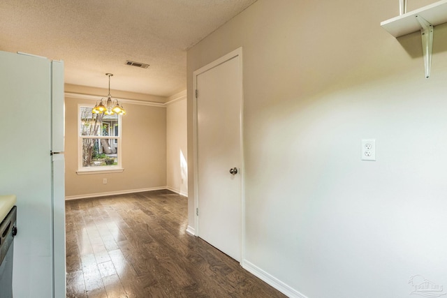 unfurnished dining area with a textured ceiling, an inviting chandelier, and dark hardwood / wood-style floors