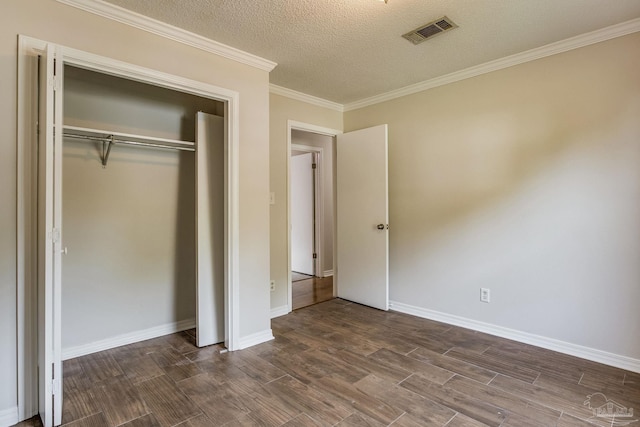 unfurnished bedroom with a textured ceiling, crown molding, dark hardwood / wood-style floors, and a closet