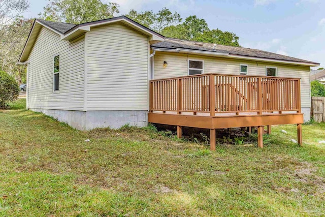 back of property featuring a deck and a lawn