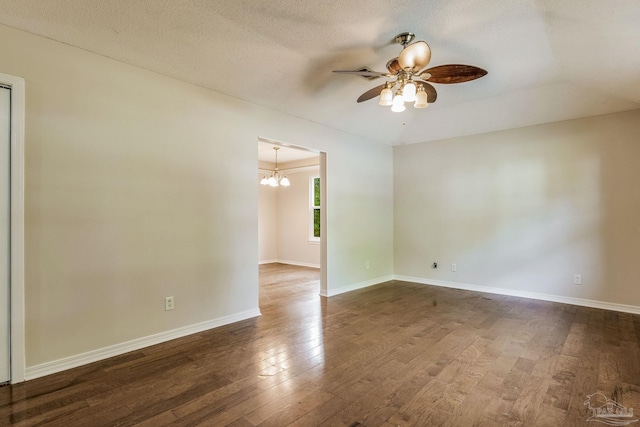 empty room featuring a textured ceiling, dark hardwood / wood-style flooring, and ceiling fan with notable chandelier