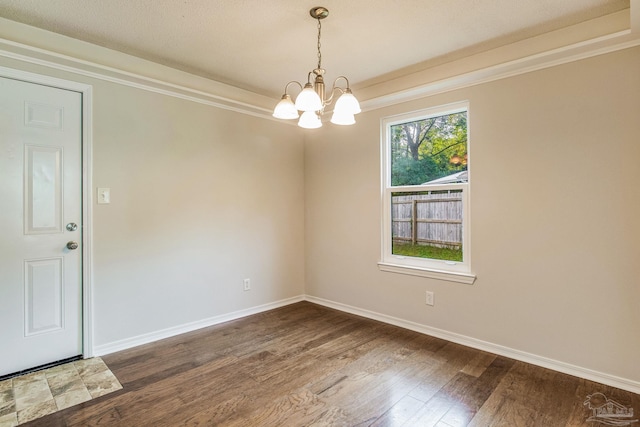 empty room featuring ornamental molding, an inviting chandelier, and dark hardwood / wood-style floors