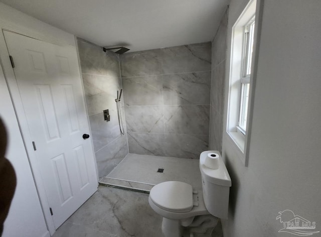 full bathroom featuring a tile shower and toilet