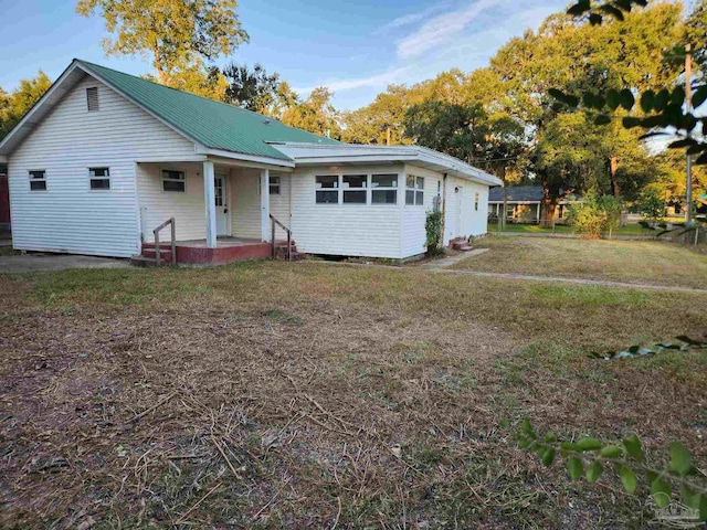 view of front of home featuring covered porch, a front lawn, and metal roof