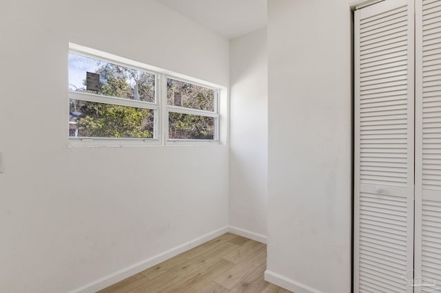 unfurnished bedroom featuring a closet, light wood-style flooring, and baseboards