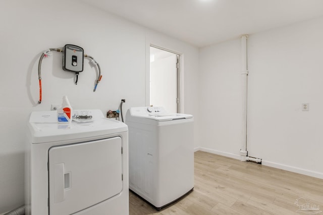 laundry room with light wood-style floors, laundry area, baseboards, and washing machine and clothes dryer