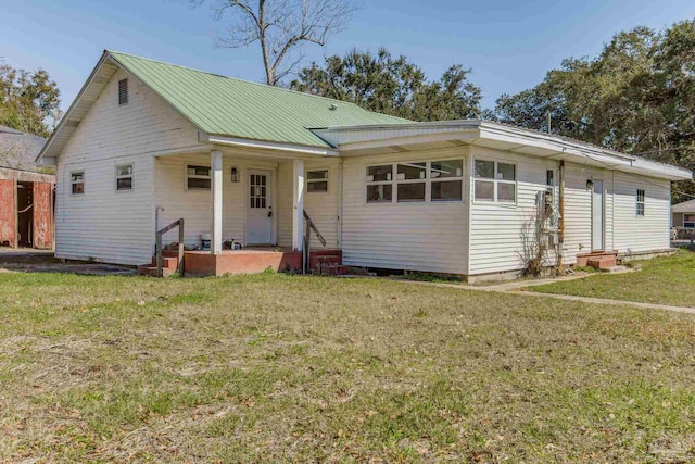 view of front of home with entry steps, metal roof, and a front yard