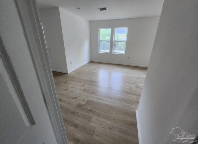 spare room with wood finished floors, visible vents, and baseboards