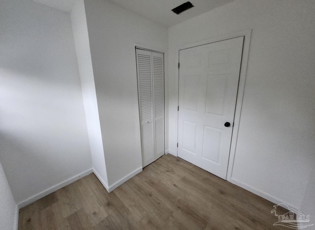 unfurnished bedroom with a closet, baseboards, and wood finished floors