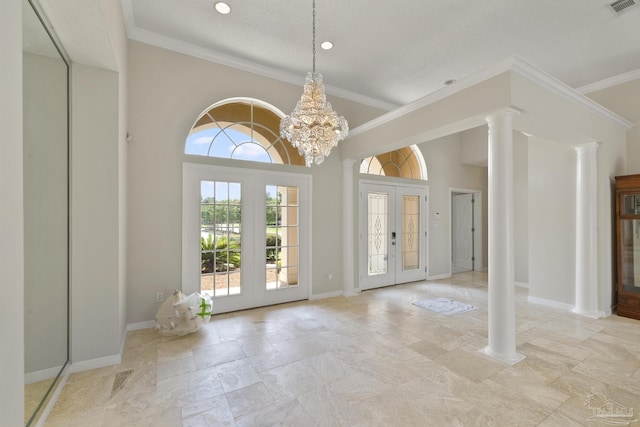 entryway with a notable chandelier, crown molding, decorative columns, and french doors