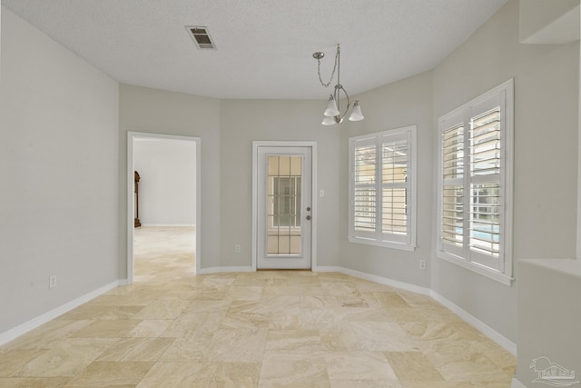 spare room featuring an inviting chandelier and a textured ceiling