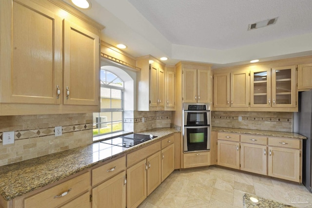 kitchen with light stone counters, tasteful backsplash, stainless steel appliances, and light brown cabinets