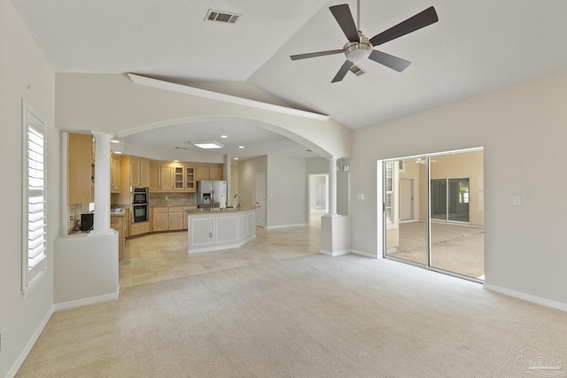 unfurnished living room featuring high vaulted ceiling, light colored carpet, decorative columns, and ceiling fan