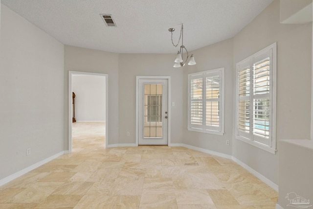 spare room featuring a chandelier and a textured ceiling