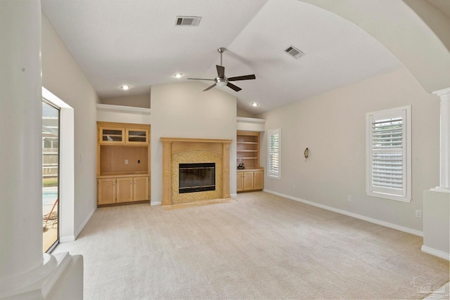 unfurnished living room with lofted ceiling, ceiling fan, a high end fireplace, light colored carpet, and ornate columns