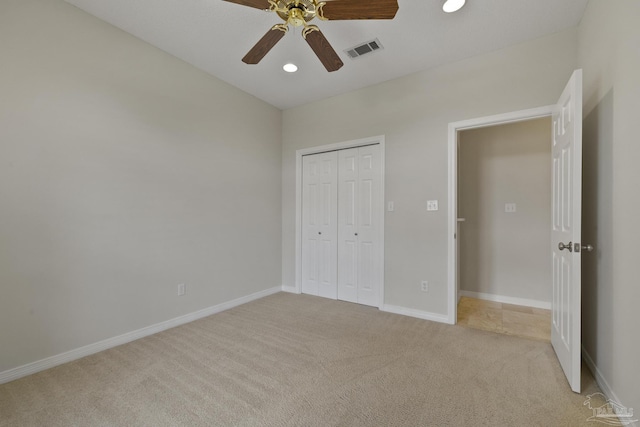 unfurnished bedroom featuring ceiling fan, light colored carpet, and a closet