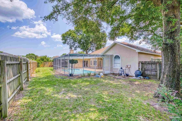 rear view of property with a fenced in pool, a lanai, and a lawn