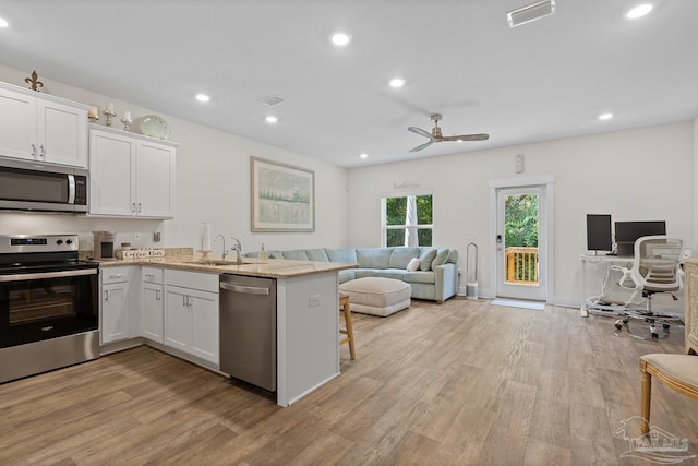 kitchen featuring visible vents, stainless steel appliances, light wood-type flooring, white cabinetry, and a sink