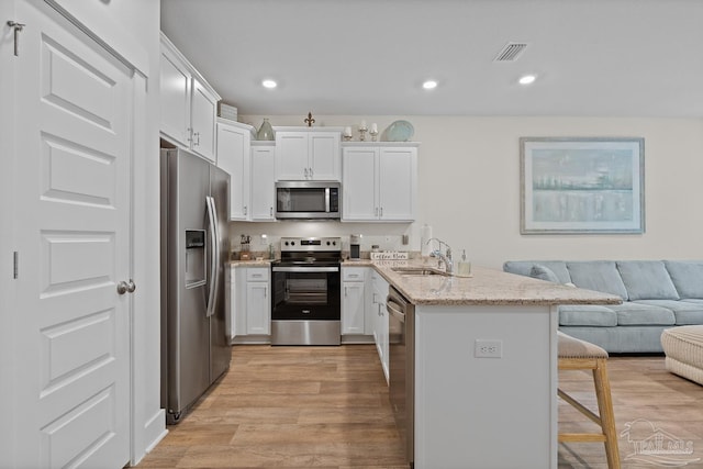 kitchen with stainless steel appliances, a breakfast bar, a sink, visible vents, and open floor plan