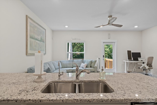 kitchen featuring recessed lighting, a sink, a ceiling fan, open floor plan, and light stone countertops