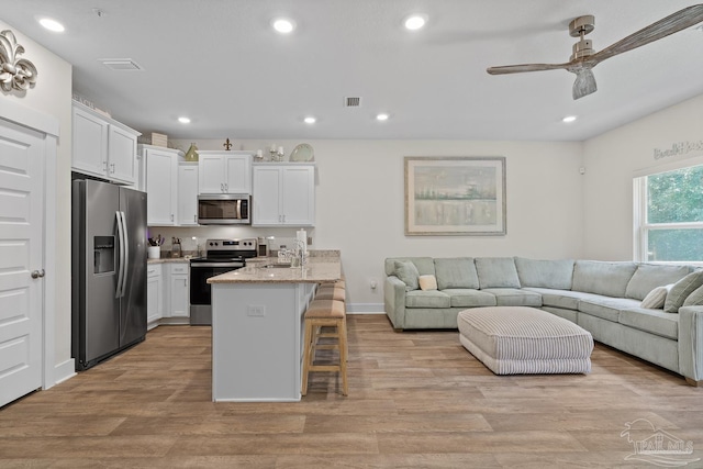 kitchen with recessed lighting, a breakfast bar, a sink, open floor plan, and appliances with stainless steel finishes