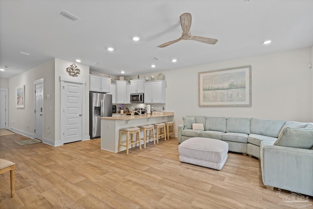 living area with light wood finished floors, visible vents, baseboards, ceiling fan, and recessed lighting