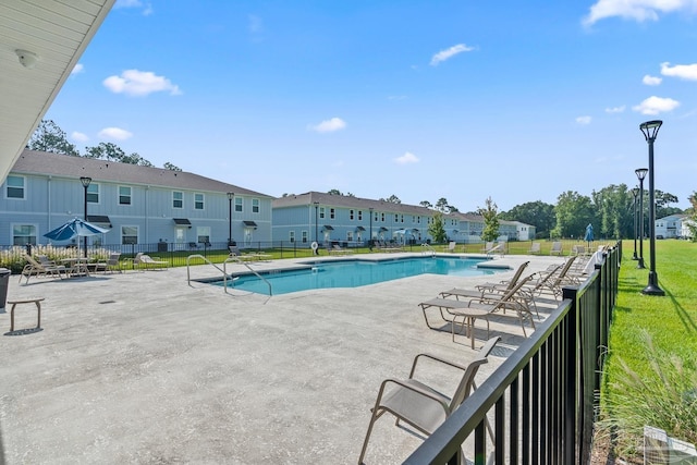 community pool featuring a yard, a residential view, fence, and a patio