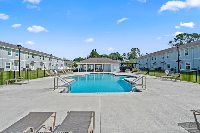 pool with a patio, a lawn, fence, and a residential view