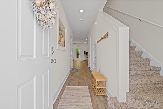 corridor featuring baseboards, stairway, wood finished floors, and recessed lighting