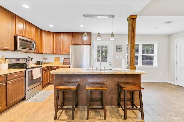 106 W Meadow Dr, Atmore, AL 36502 - kitchen featuring appliances with stainless steel finishes, a sink, light wood-type flooring, a breakfast bar, and a kitchen island with sink