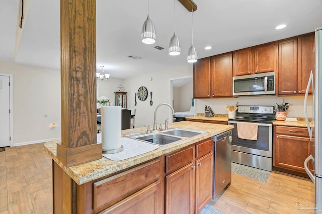 106 W Meadow Dr, Atmore, AL 36502 - kitchen featuring appliances with stainless steel finishes, a sink, decorative light fixtures, light wood-style floors, and brown cabinetry