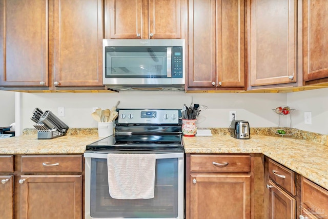 106 W Meadow Dr, Atmore, AL 36502 - kitchen with stainless steel appliances, light stone countertops, and brown cabinets