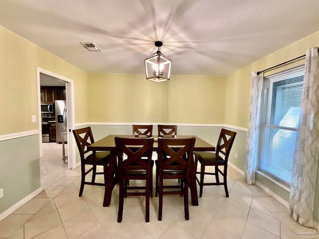 dining area with a notable chandelier, light tile patterned floors, and a textured ceiling