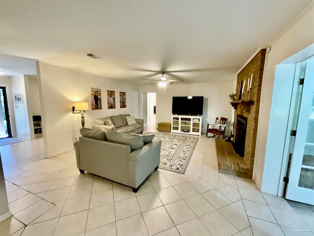 living room featuring a brick fireplace, ceiling fan, and light tile patterned flooring