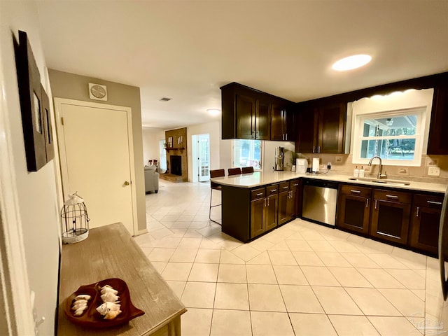 kitchen featuring kitchen peninsula, dark brown cabinetry, sink, light tile patterned floors, and dishwasher