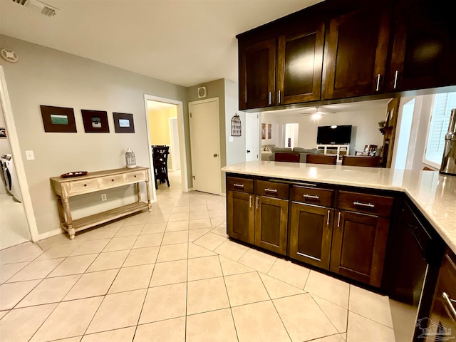 kitchen featuring kitchen peninsula, light tile patterned floors, separate washer and dryer, and dark brown cabinets