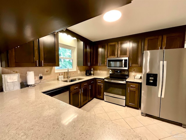 kitchen featuring sink, stainless steel appliances, tasteful backsplash, dark brown cabinets, and light tile patterned flooring