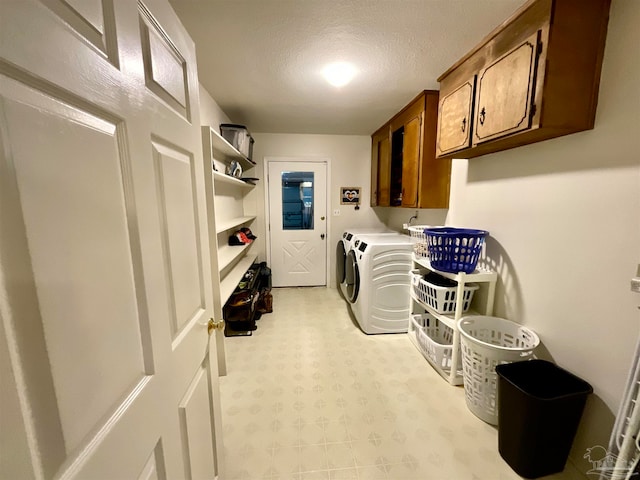 washroom featuring cabinets, washing machine and dryer, and a textured ceiling