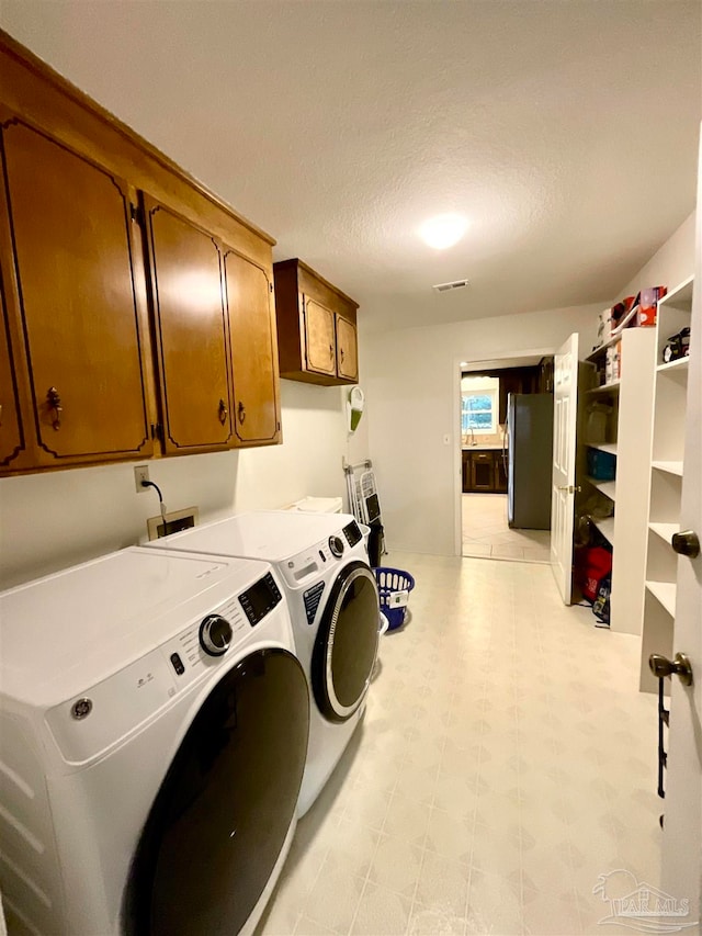 clothes washing area featuring cabinets, independent washer and dryer, and a textured ceiling