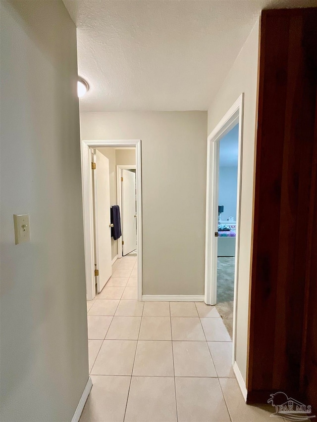 corridor with light tile patterned floors and a textured ceiling