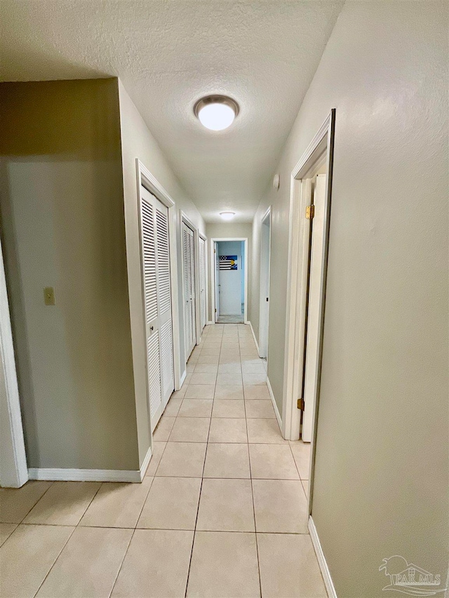 hallway with light tile patterned flooring and a textured ceiling