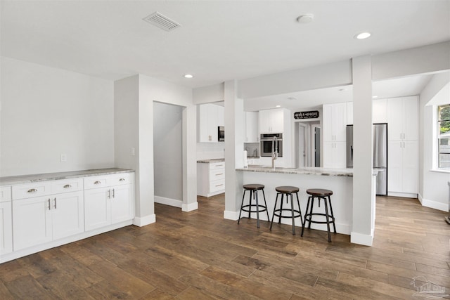 9852 Hillview Dr, Pensacola, FL 32514 - kitchen featuring appliances with stainless steel finishes, a kitchen bar, dark wood-style flooring, white cabinetry, and recessed lighting