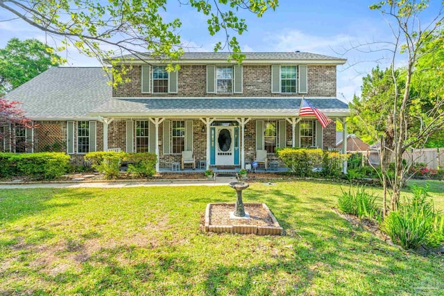view of front of home featuring brick siding, a front lawn, and a porch