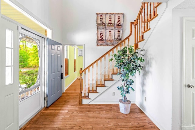 foyer entrance with stairs, baseboards, and wood finished floors