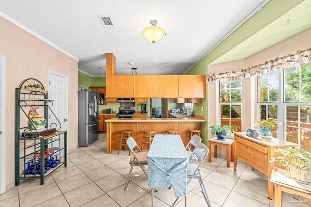 kitchen featuring exhaust hood, ornamental molding, light countertops, appliances with stainless steel finishes, and a peninsula