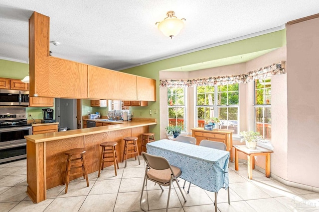 kitchen featuring stainless steel appliances, a sink, a textured ceiling, and crown molding