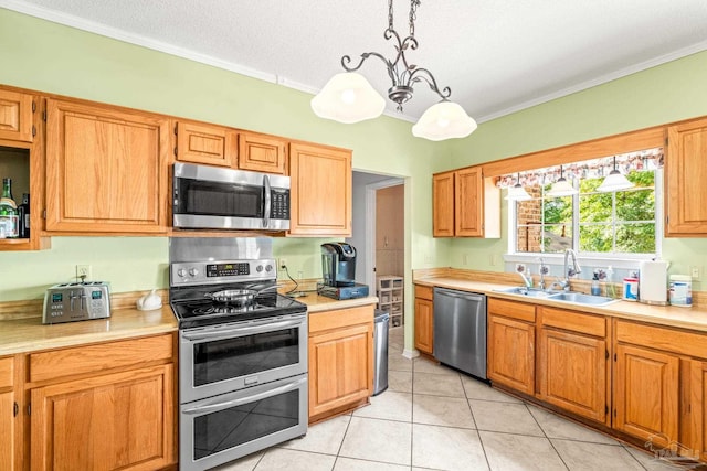 kitchen with a sink, ornamental molding, light countertops, and appliances with stainless steel finishes