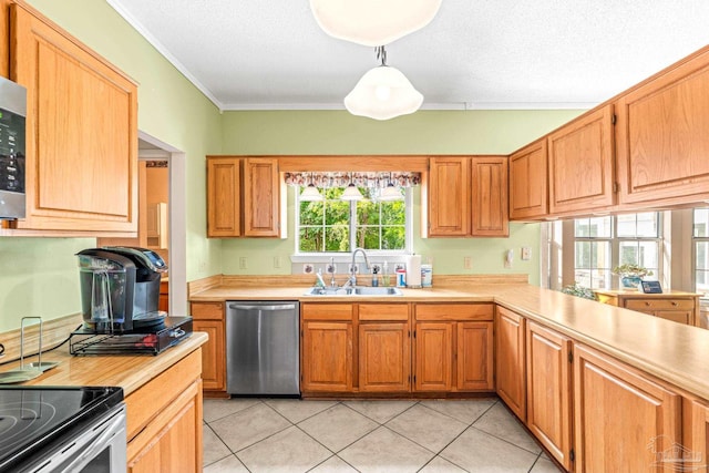 kitchen with light tile patterned floors, a sink, light countertops, appliances with stainless steel finishes, and crown molding