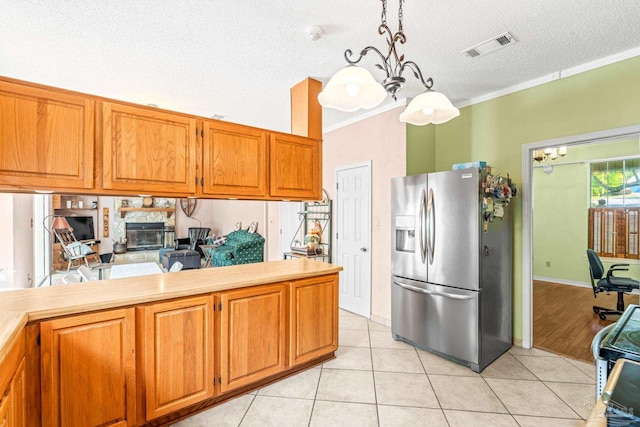 kitchen featuring crown molding, light tile patterned floors, stainless steel fridge, and brown cabinets