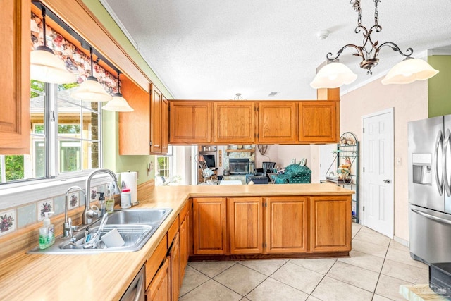 kitchen with a textured ceiling, light tile patterned flooring, light countertops, a sink, and stainless steel fridge