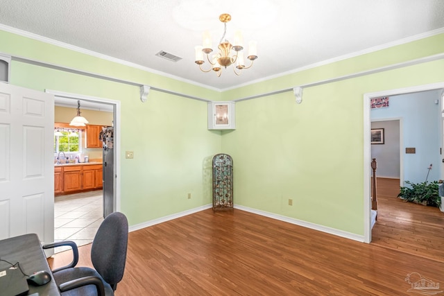 office area featuring light wood finished floors, visible vents, an inviting chandelier, and ornamental molding